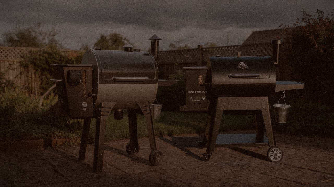 Camp Chef Woodwind WiFi 24 and Pit Boss Navigator 850 at night with smoke, wood pellet grills on a dark patio