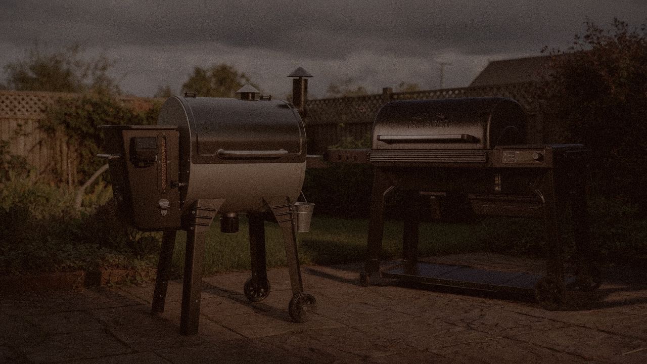 Camp Chef Woodwind Pro WiFi 24 and Traeger Pro 780 at night with smoke, wood pellet grills on a dark patio