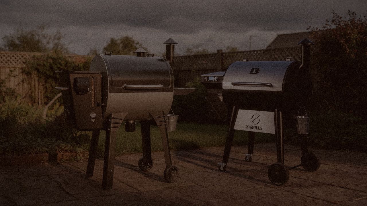 Camp Chef Woodwind Pro WiFi 24 and Z Grills 700 Series (ZPG-7002) at night with smoke, wood pellet grills on a dark patio