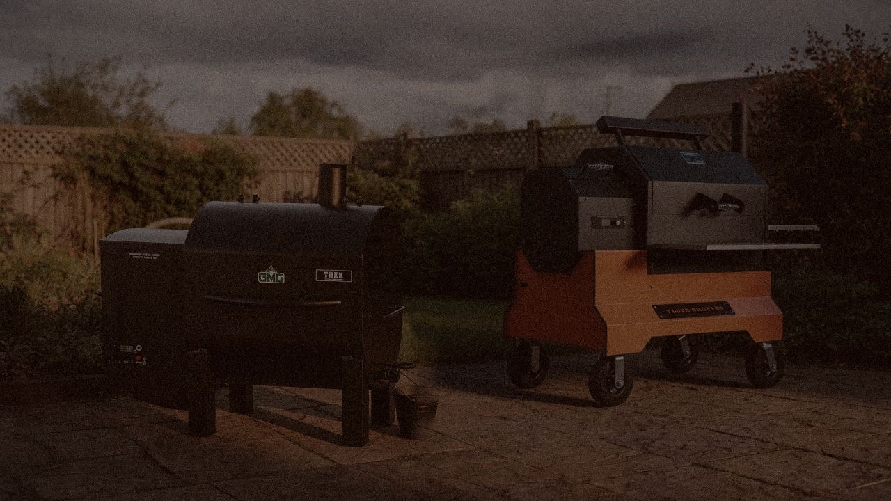 Green Mountain Grills Trek and Yoder Smokers YS640s at night with smoke, wood pellet grills on a dark patio