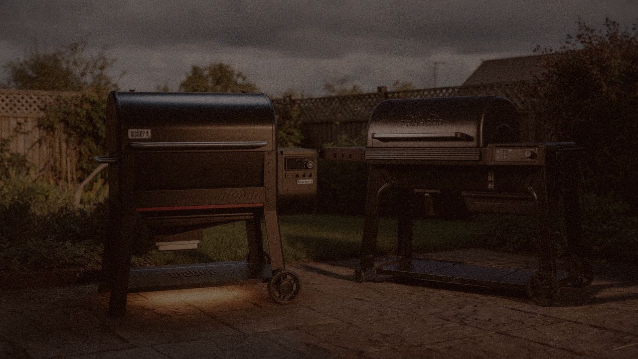 Weber Searwood XL 600 and Traeger Pro 780 at night with smoke, wood pellet grills on a dark patio