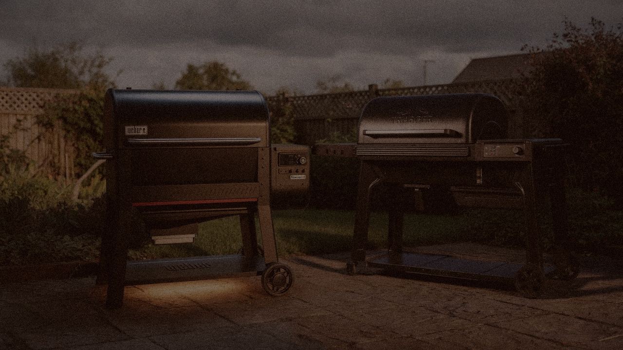 Weber Searwood XL 600 and Traeger Woodridge Pro at night with smoke, wood pellet grills on a dark patio